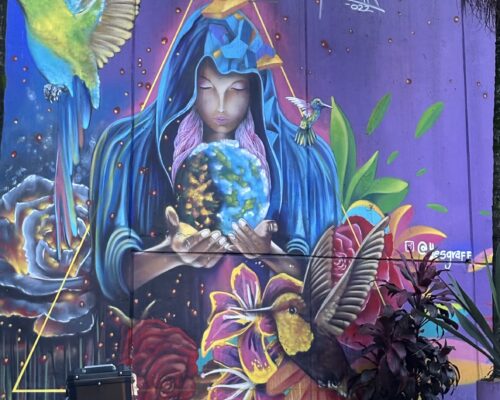 Colorful mural of a woman holding a ball of the world surrounded by birds and flowers