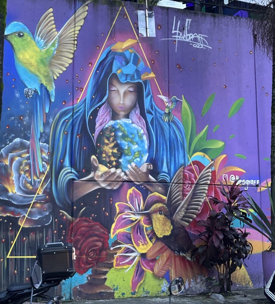Colorful mural of a woman holding a ball of the world surrounded by birds and flowers